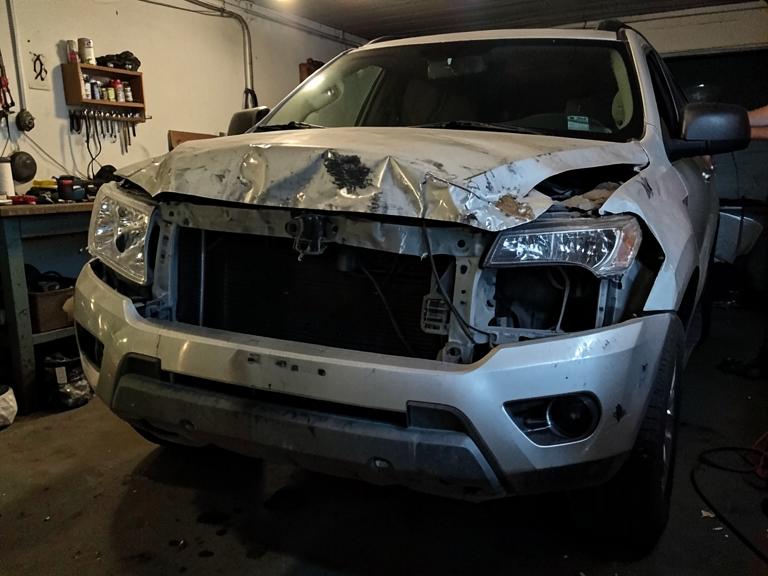 SUV front end with crumpled hood damage before repair